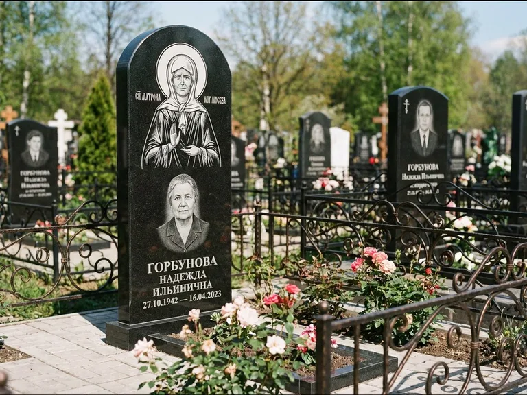 Памятник с гравировкой иконы: стела с арочным верхом и киотом под образ — гравировка образа Матроны Московской, гранитный цоколь с тёмной плиткой, работа «Ковалёв» в Хабаровске