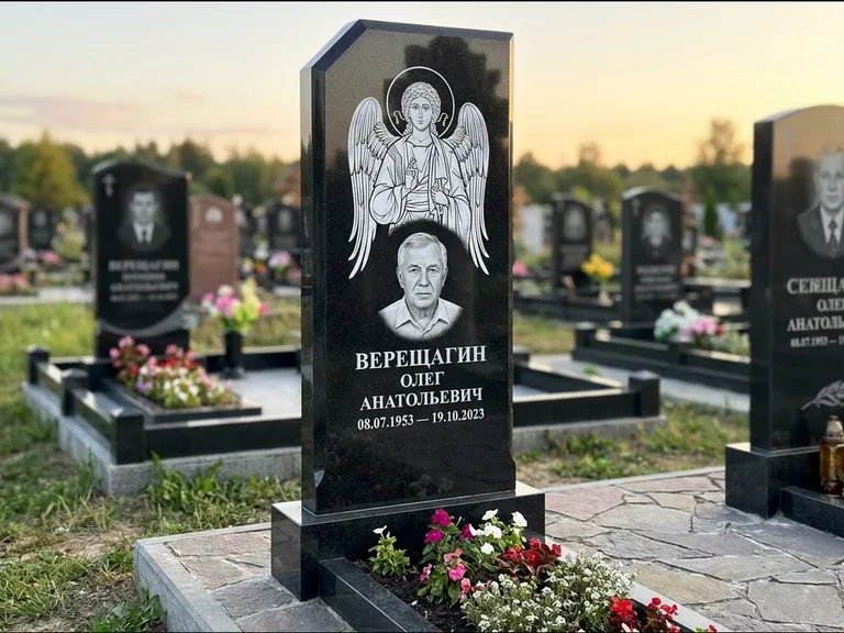 Памятник с гравировкой иконы: стела с резным навершием и нимбом в золоте — гравировка образа Спасителя, высокие разросшиеся туи полукругом, работа «Мельникова» в Хабаровске