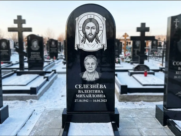 Памятник с гравировкой иконы: небольшая скромная одиночная стела с именной иконой — золочёный нимб на образе, аккуратный участок с газоном, работа «Ковалёв» в Хабаровске