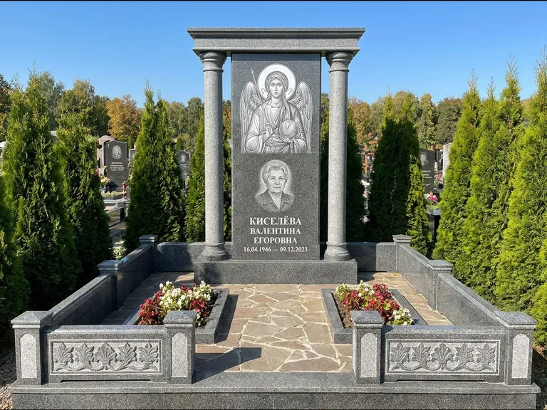 Памятник с гравировкой иконы: массивная стела с двускатным навершием-домиком — гравировка Николая Чудотворца, живая изгородь из туи, работа «Журавлёв» в Хабаровске