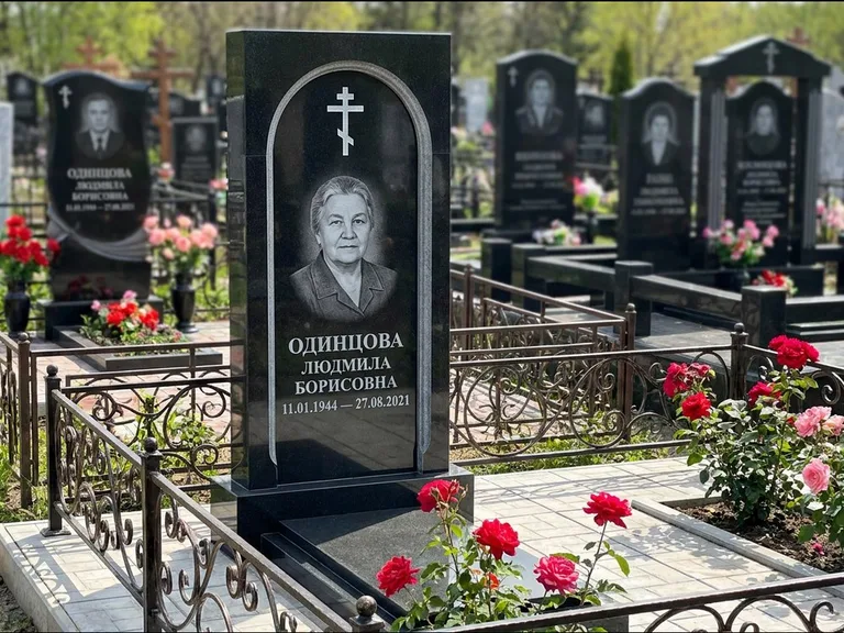 Памятник из чёрного гранита — скромная невысокая стела с крестом с терновым венцом, работа «Лаврентьева» в Хабаровске